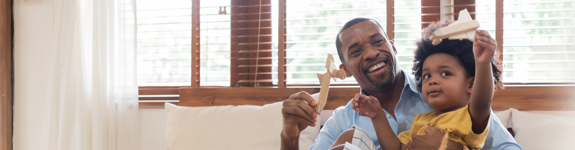 father and son playing with toy planes on the couch